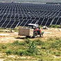 Tractor in front of a field of solar panels. 
